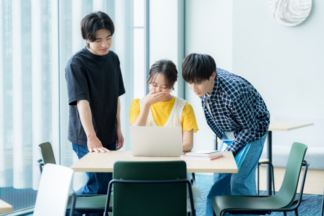 パソコンの画面を見つめ話し合う3人の男女の写真
