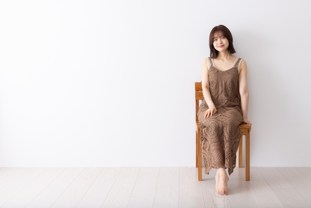 椅子に座るワンピースを着た若い女性の写真