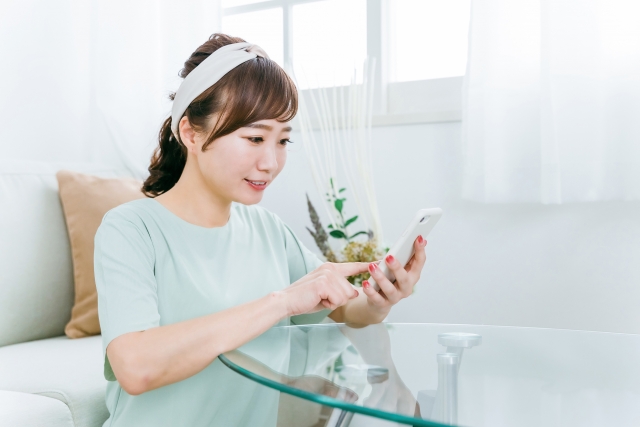 スマホで調べ物をしているヘアバンドをした女性の写真
