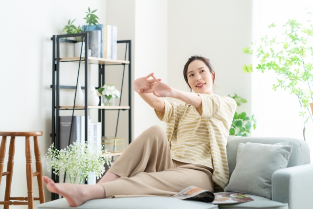 背伸びをする部屋の中で座っている女性の写真