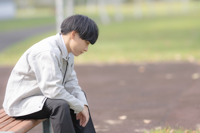 俯いて落ち込んでいる若い男性の写真