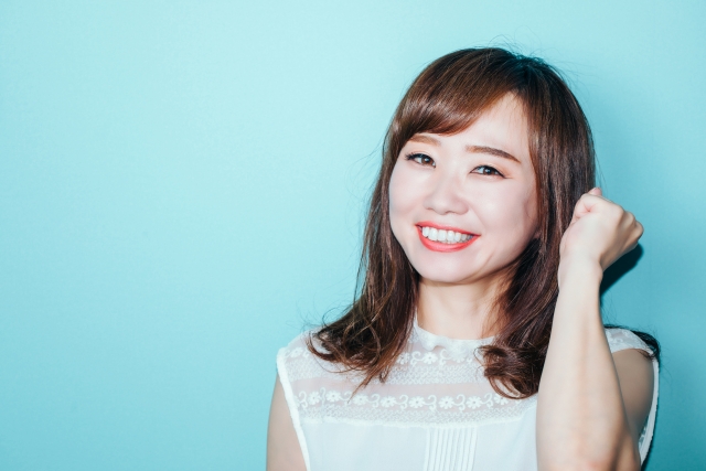 ガッツポーズをしながら微笑む若い女性の写真