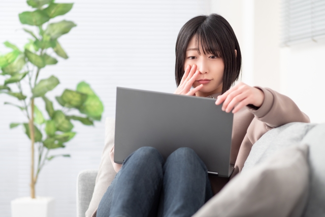 PCを見ながら涙ぐむ若い女性の写真